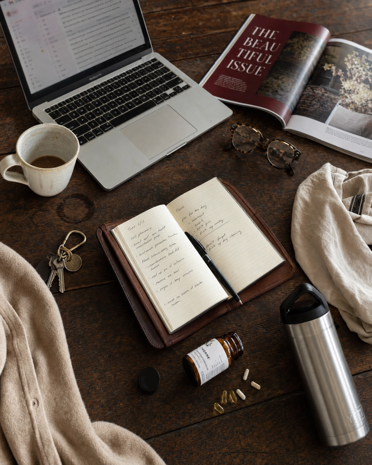 Routine flatlay with journal, coffee, laptop, and supplements